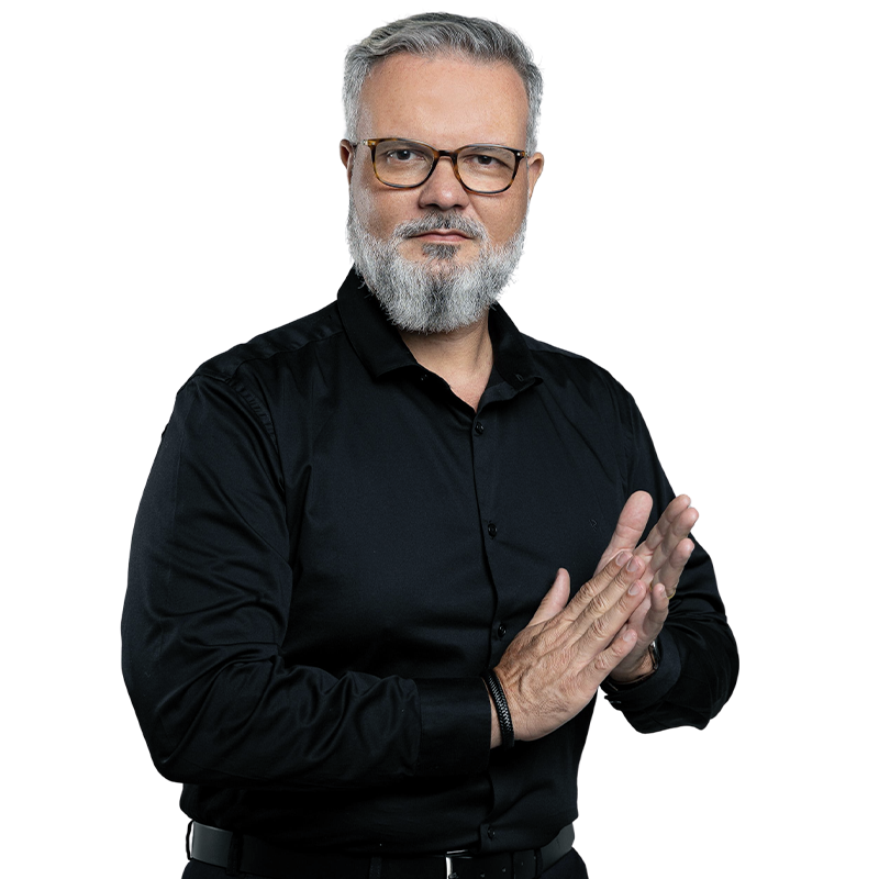 Alexandre de Salles, de camisa preta, olhando para a câmera com as mãos unidas na frente do corpo.