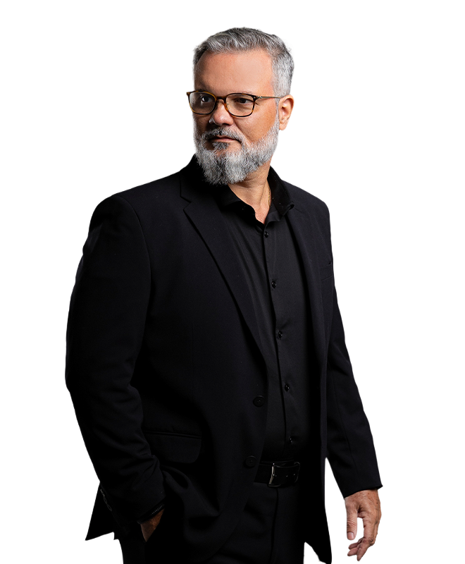 Alexandre de Salles em pé, com barba e cabelos grisalhos, vestindo um terno preto e olhando para o lado.